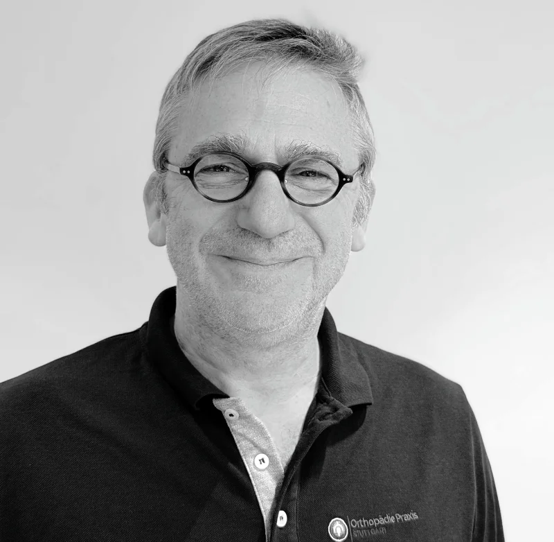 Dr. med. Burkhardt, Orthopäde, Rotebühlplatz 17, Stuttgart Portrait von Dr. P. Burkhardt, lächelnd, mit Brille im Poloshirt mit der Aufschrift Orthopädie Praxis Stuttgart