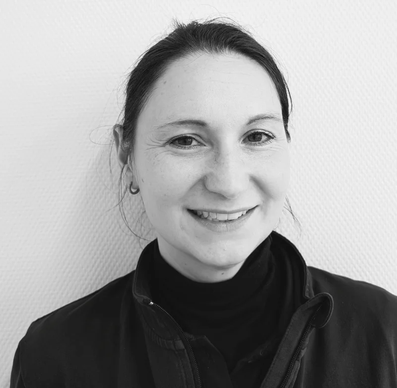 Portrait Dr. Lena Welte, eine Frau mit dunklen, langen Haaren, Ohrstecker und freundlichen Lachfalten um die Augen.